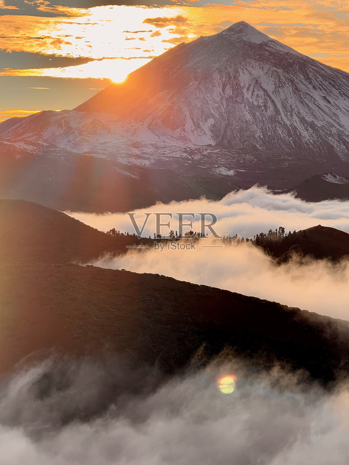 日落时分,白雪覆盖的特德峰与翻滚的云朵照片摄影图片