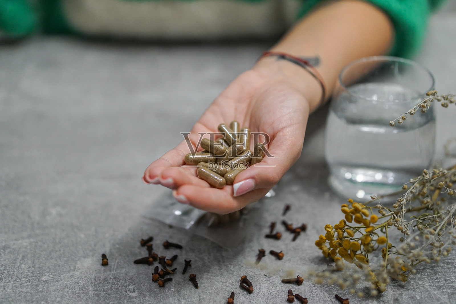女性手握着用艾草、丁香和多种天然草药制成的手工抗寄生虫排毒胶囊,旨在进行整体清洁。照片摄影图片