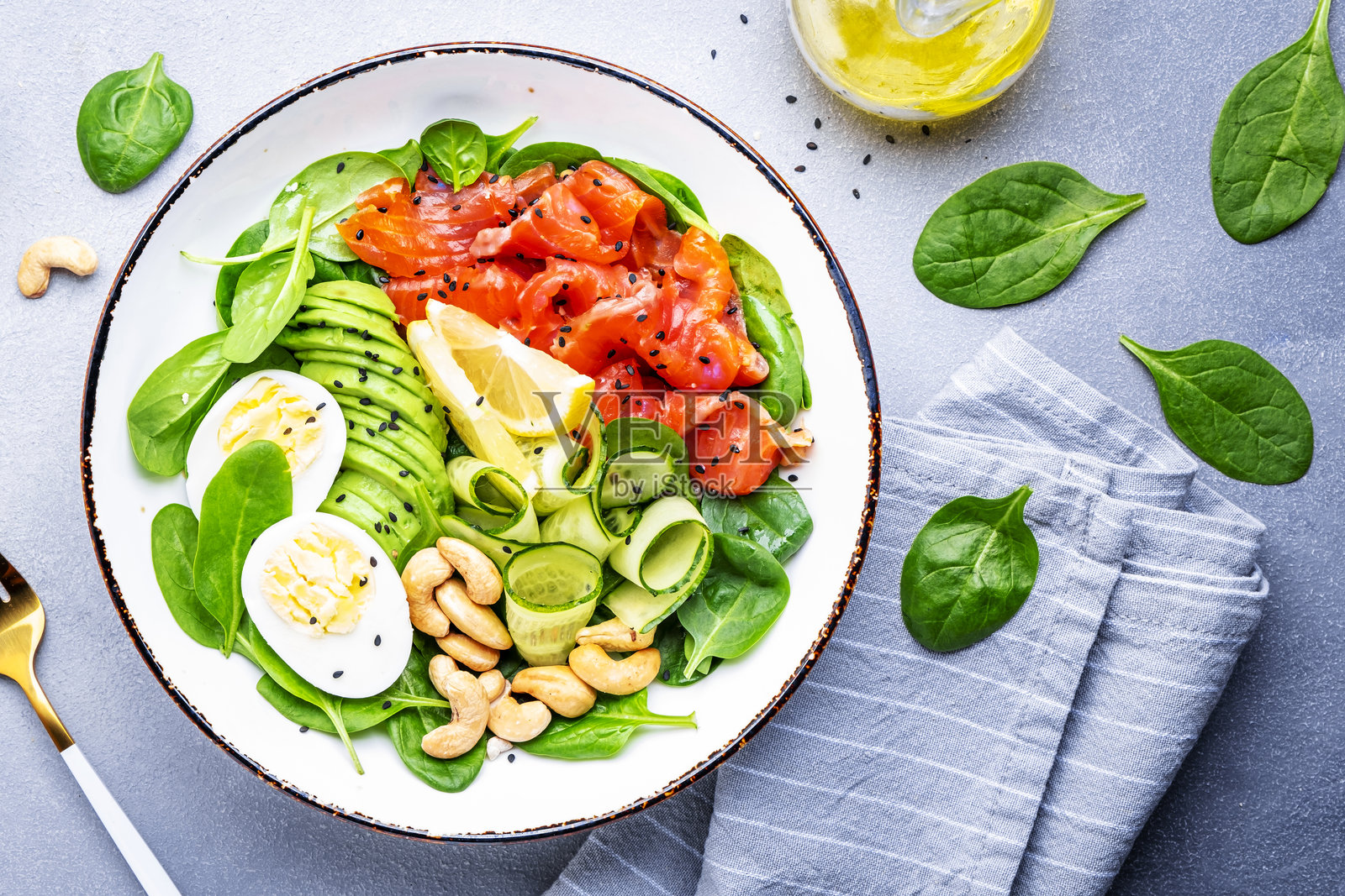 含有三文鱼、鳄梨、菠菜、鸡蛋和腰果的生酮饮食沙拉。灰色桌面背景,俯视图。照片摄影图片