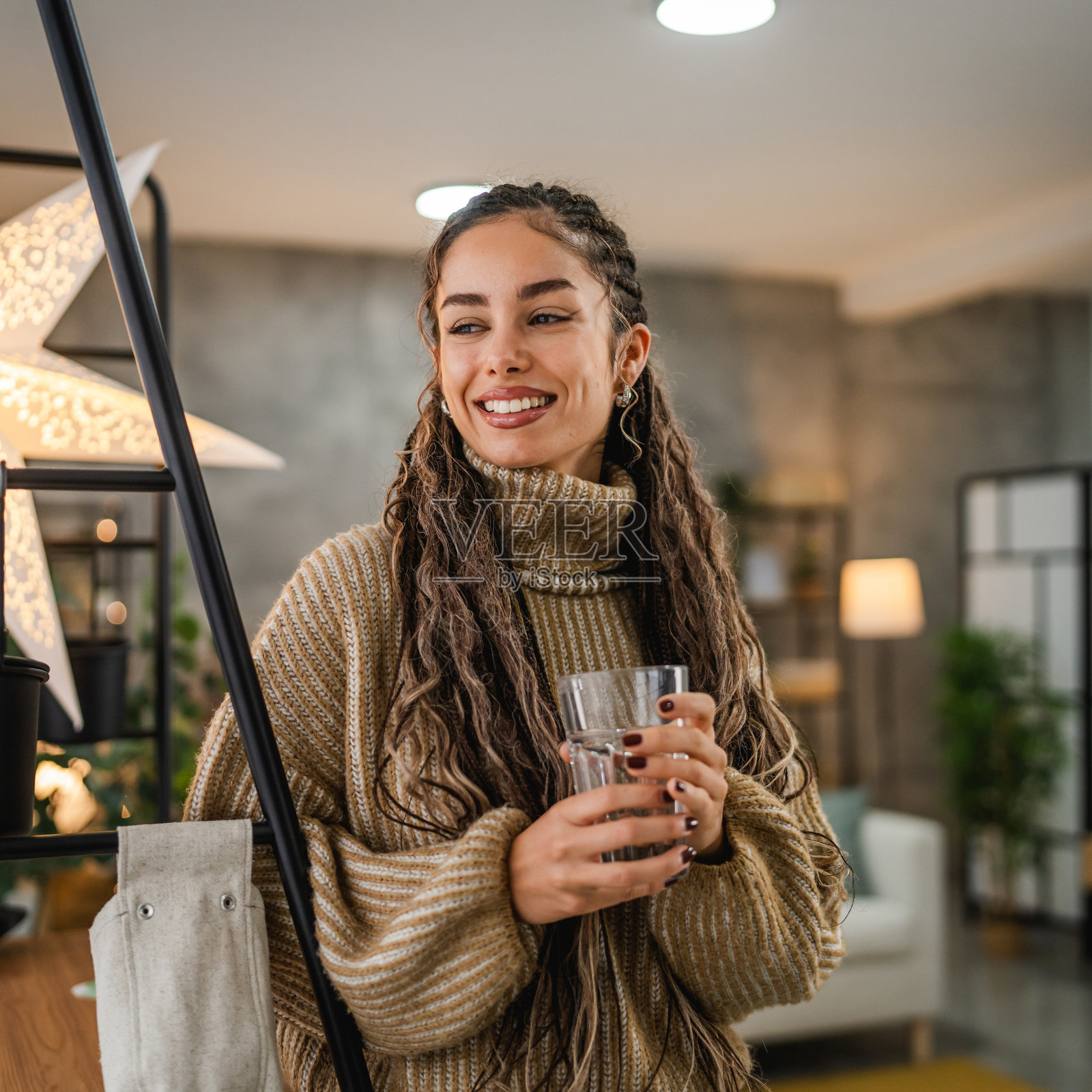 年轻女性在家中放松,手中拿着一杯水的肖像照片摄影图片