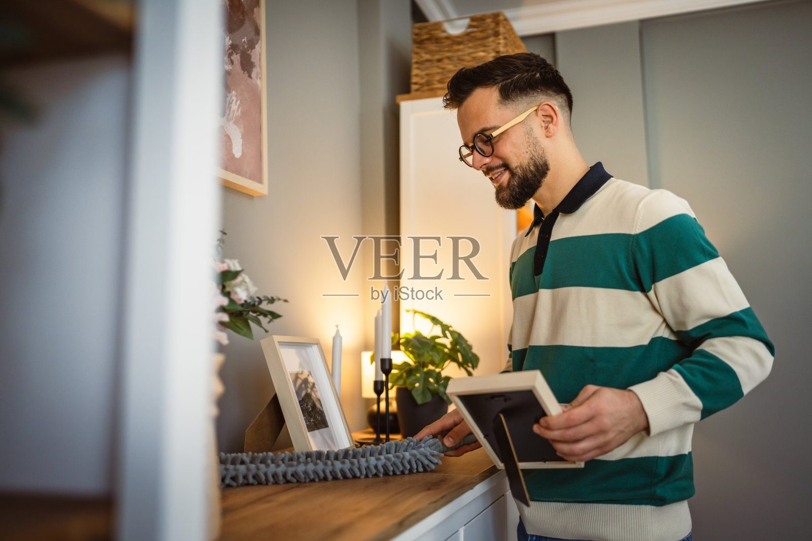 成年男子在室内做家务,擦拭书架并用抹布清洁。照片摄影图片