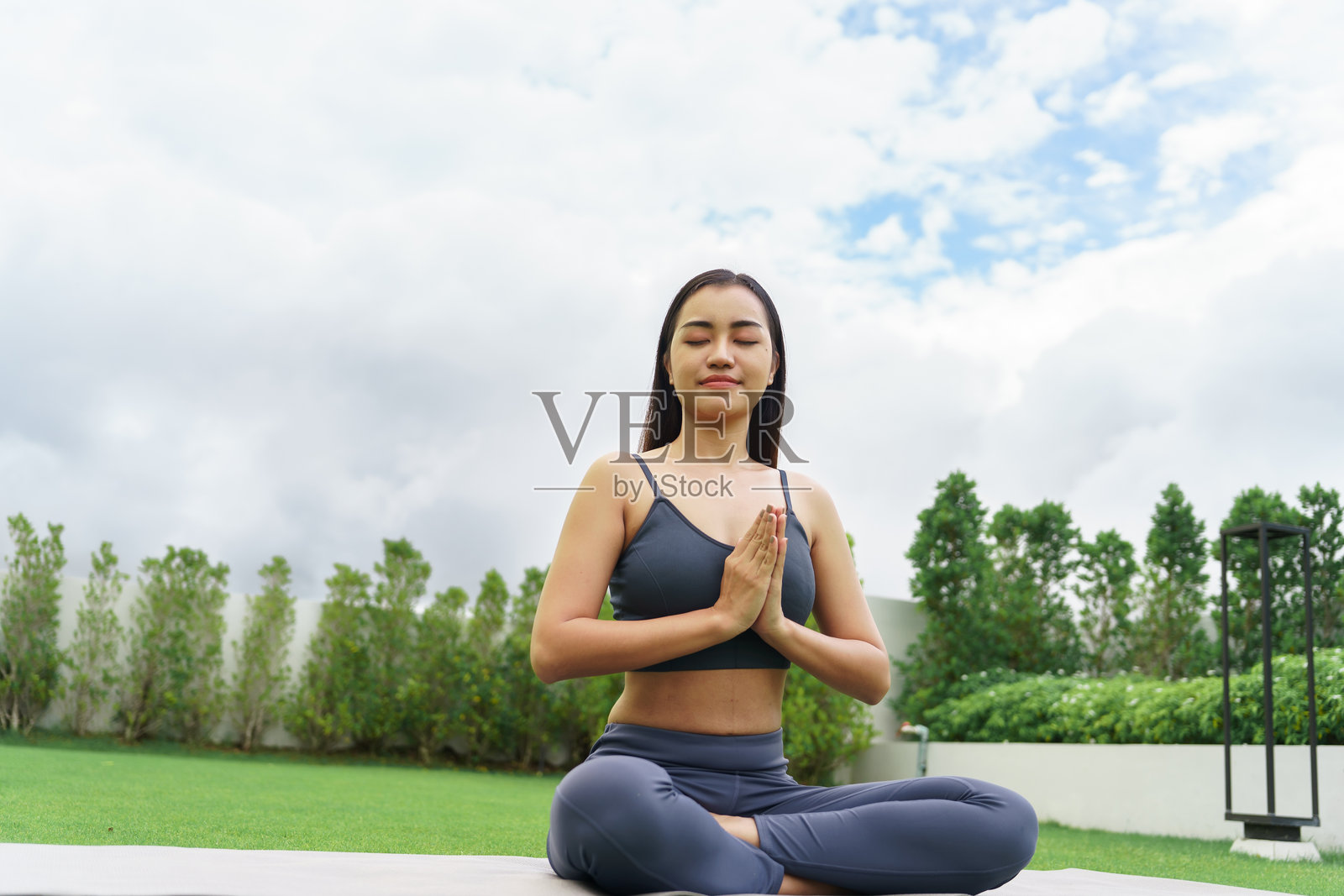 美丽自信的亚洲女性在绿色公园中练习瑜伽,享受大自然的放松。早晨的公园里,亚洲女孩展现出宁静、真诚与平和,展现运动员的健康与活力。照片摄影图片