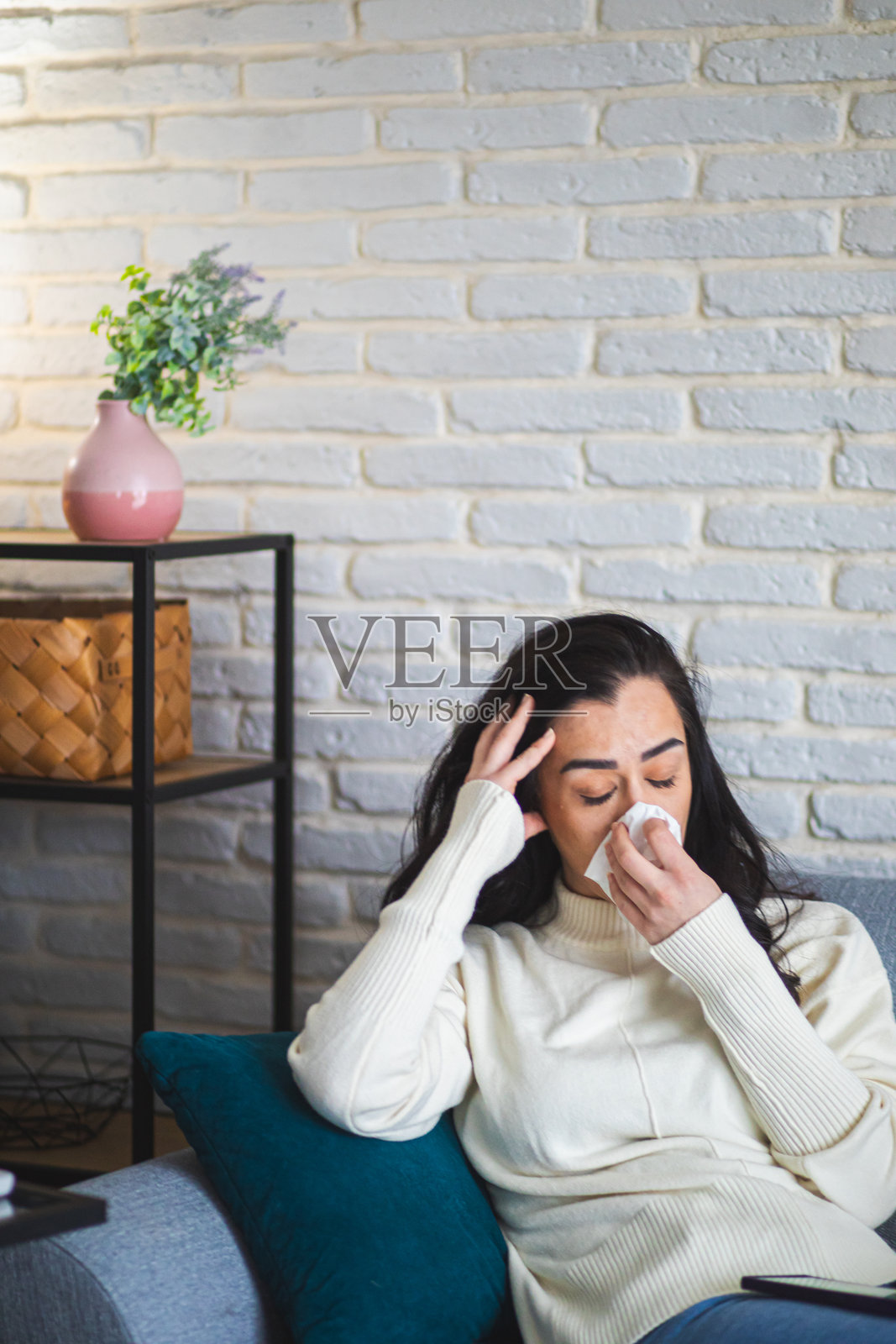 生病的女人坐在沙发上,用手帕擦鼻子照片摄影图片