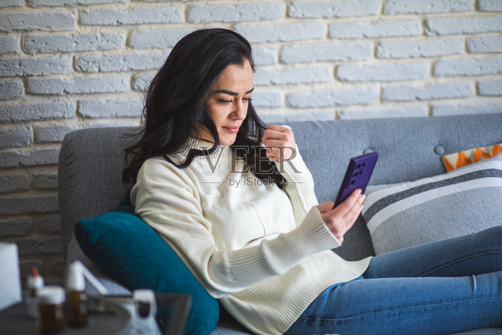 生病的女人在家沙发上休息并使用智能手机照片摄影图片