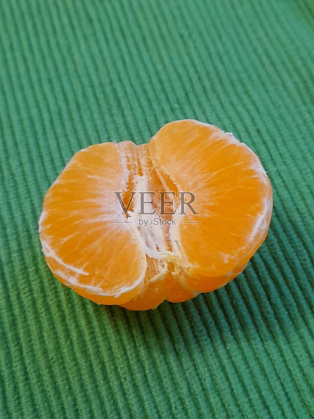 剥皮的半个橘子与绿色背景照片摄影图片