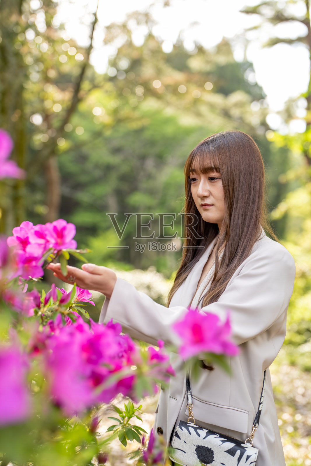 一位20多岁的日本女性穿着白色衣服,在日本一个自然丰富的公园里度过时光。照片摄影图片