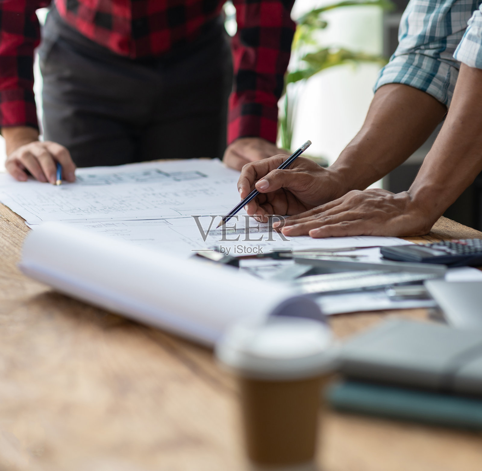 建筑师和工程师的头脑风暴小组在办公室的木桌上讨论建筑蓝图设计文件和施工项目规划。照片摄影图片