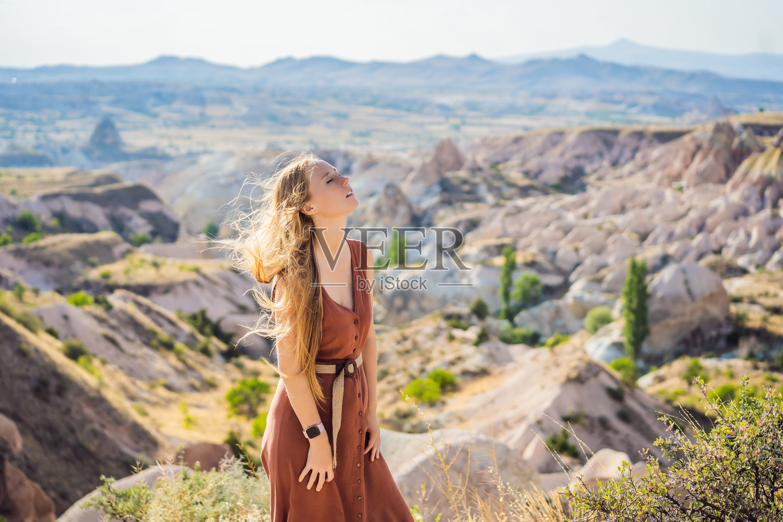 年轻女性在土耳其卡帕多奇亚的戈雷梅附近探索岩石形成和仙女洞穴的山谷照片摄影图片