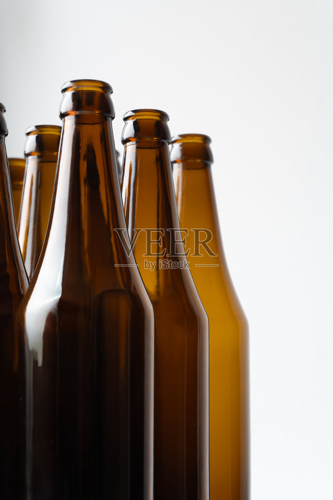 几只棕色玻璃啤酒瓶的特写,整齐地排列在一起,表面光滑,质感反射。照片摄影图片