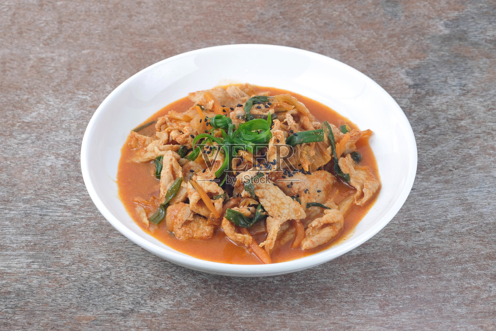 白色陶瓷盘中的泡菜炒猪肉,放在木桌上。照片摄影图片