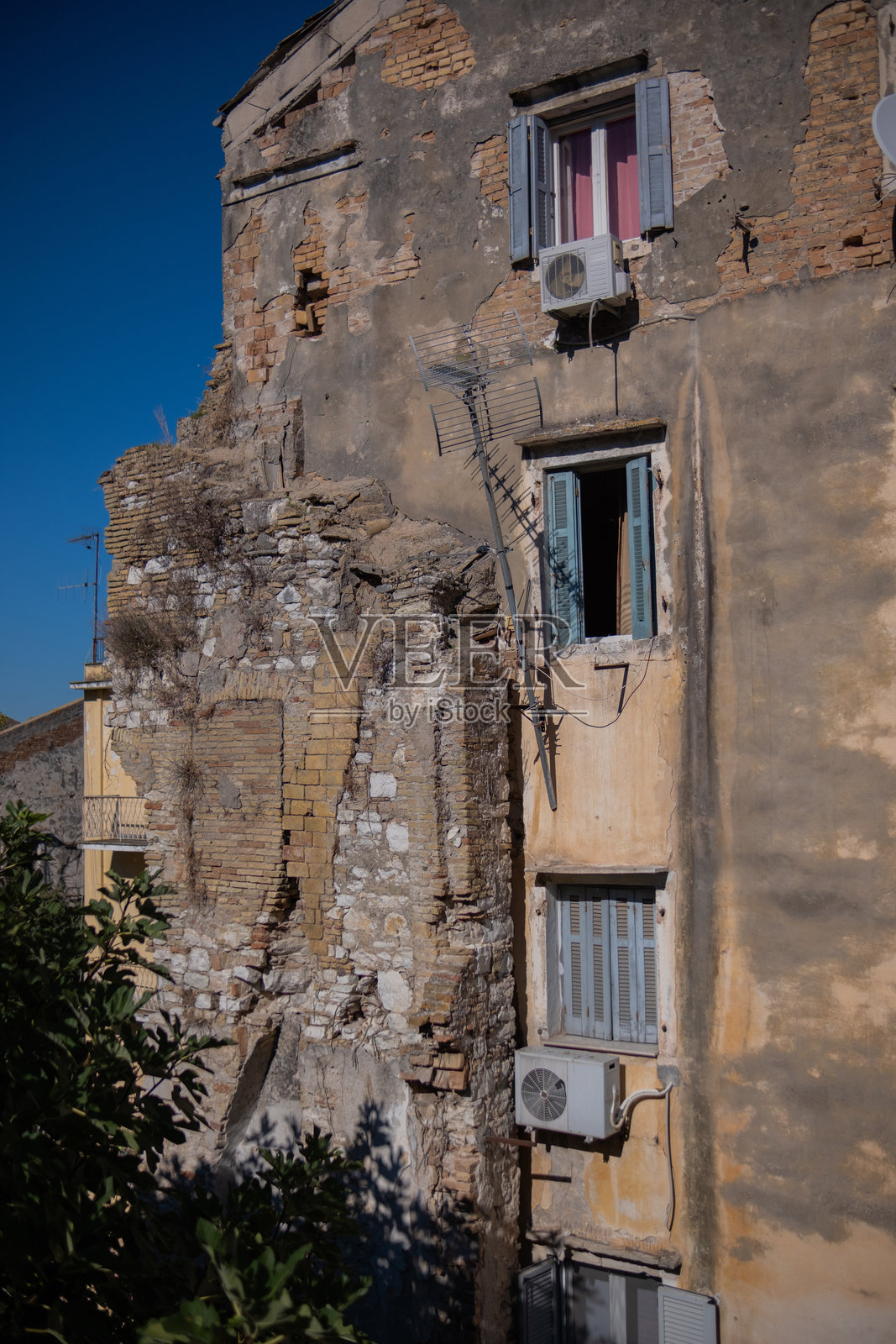 一栋状况极差的老旧多层住宅楼。混乱的石材结构,墙壁开裂,修复不当的损坏。一个奇怪且外观不佳的公寓楼,仍然有居民居住。照片摄影图片