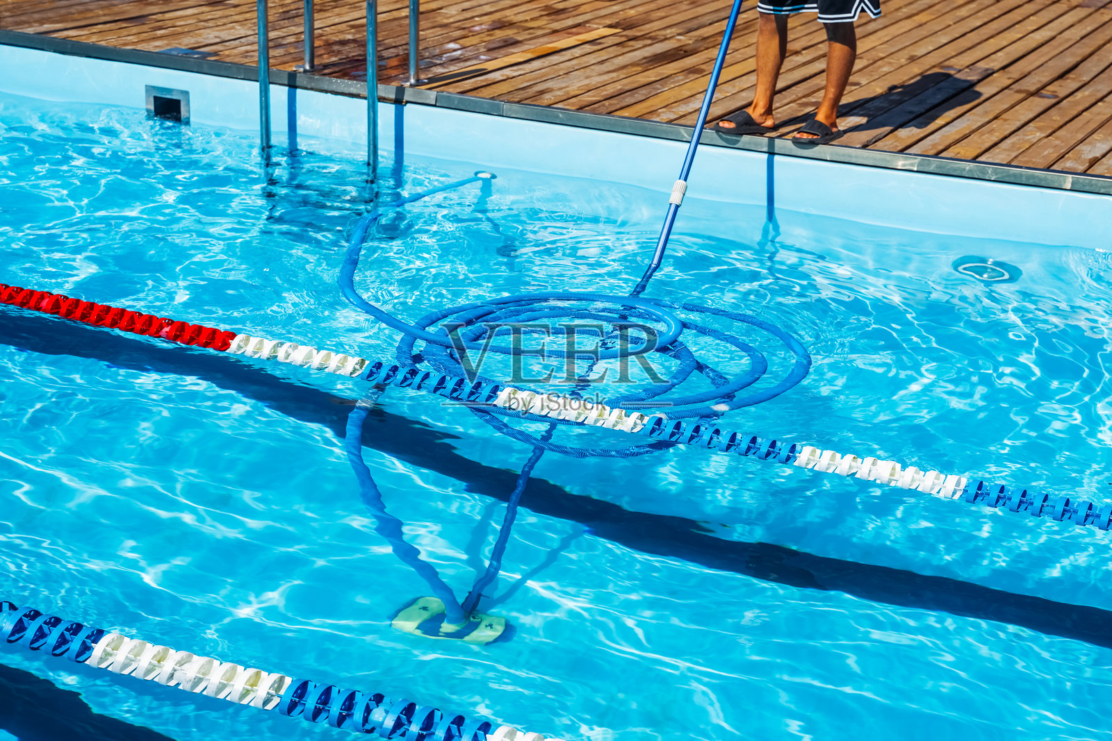 使用吸尘软管进行泳池维护和清洁。人们正在用吸尘软管清洁泳池。特写镜头展示一个人在清洁泳池。照片摄影图片