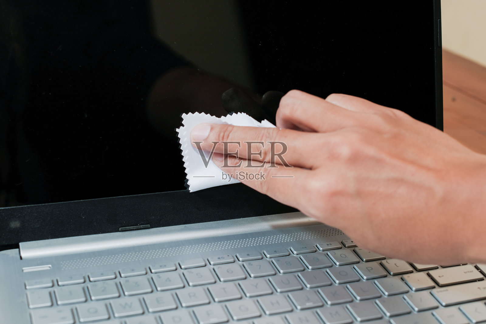 特写镜头:男子用布清洁笔记本电脑屏幕上的灰尘照片摄影图片