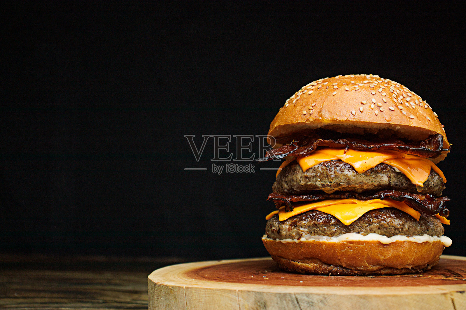 美味的双层手工汉堡,配有双份切达奶酪、特制白酱、脆皮培根和芝麻面包。照片摄影图片