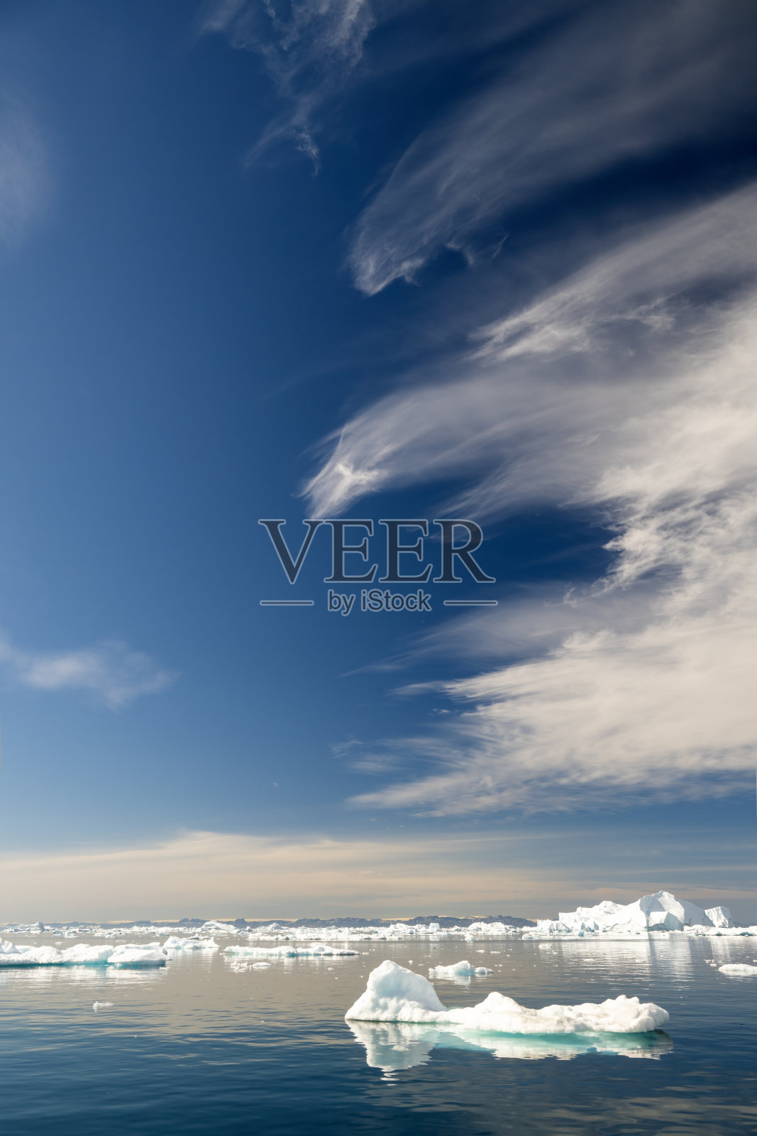 格林兰伊卢利萨特的迪斯科湾地区,冰山与奇特云彩下的壮丽天空的垂直风景照片摄影图片