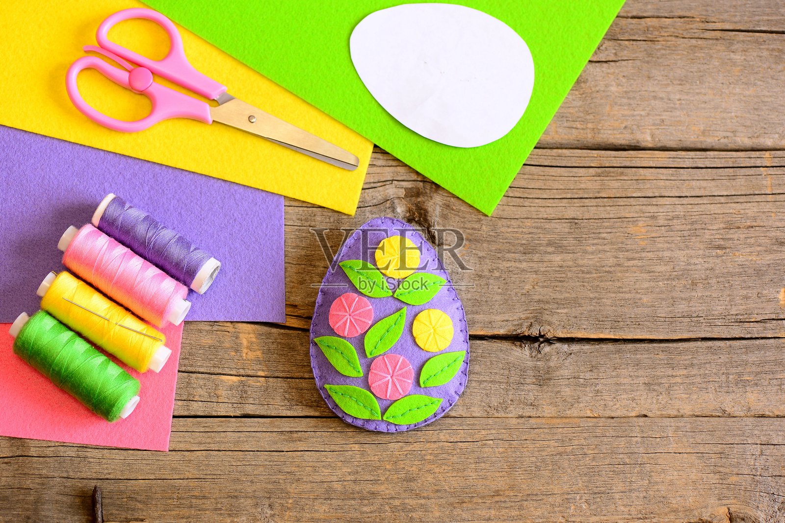 一个迷人的毛毡复活节彩蛋装饰,配有花朵和叶子。简单的复活节艺术手工艺。俯视图照片摄影图片