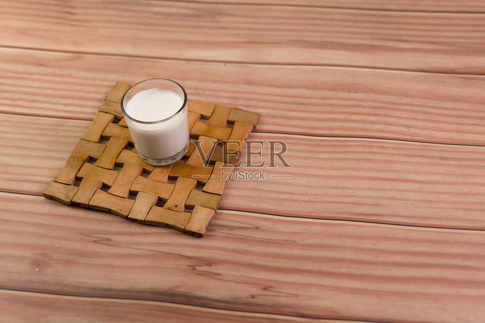 一杯牛奶放在木质杯垫上照片摄影图片