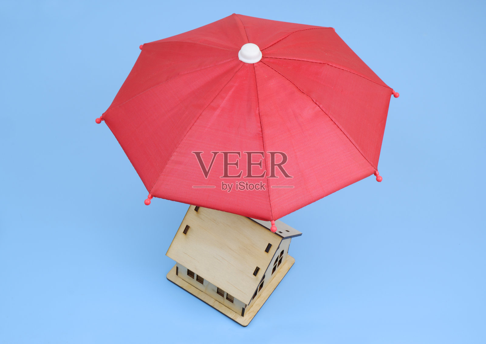 蓝色背景下的伞下木屋模型。照片摄影图片