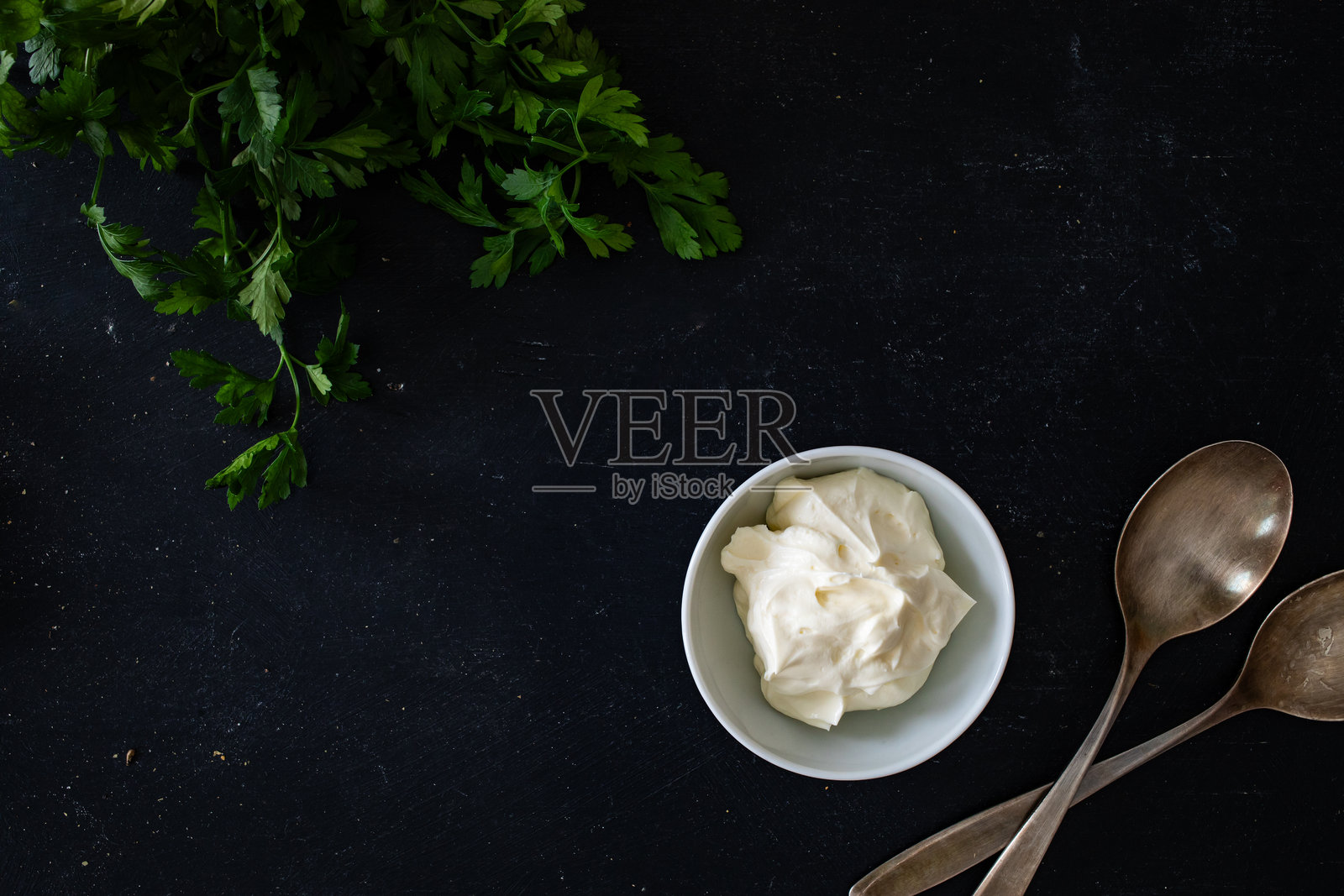 空黑色餐桌上放着香菜、勺子和旁边的酸奶油照片摄影图片