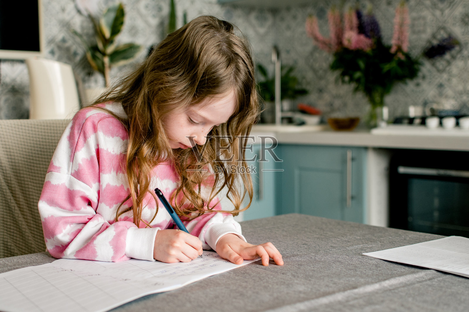 在家做作业的女学生,正在笔记本上写字。照片摄影图片