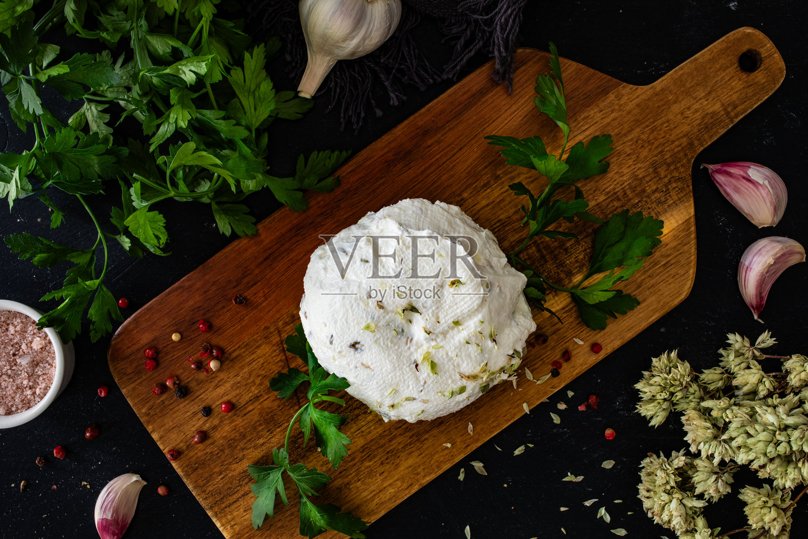自制的奶酪涂抹酱,配有大蒜和牛至,放在黑色桌子上的切菜板上照片摄影图片