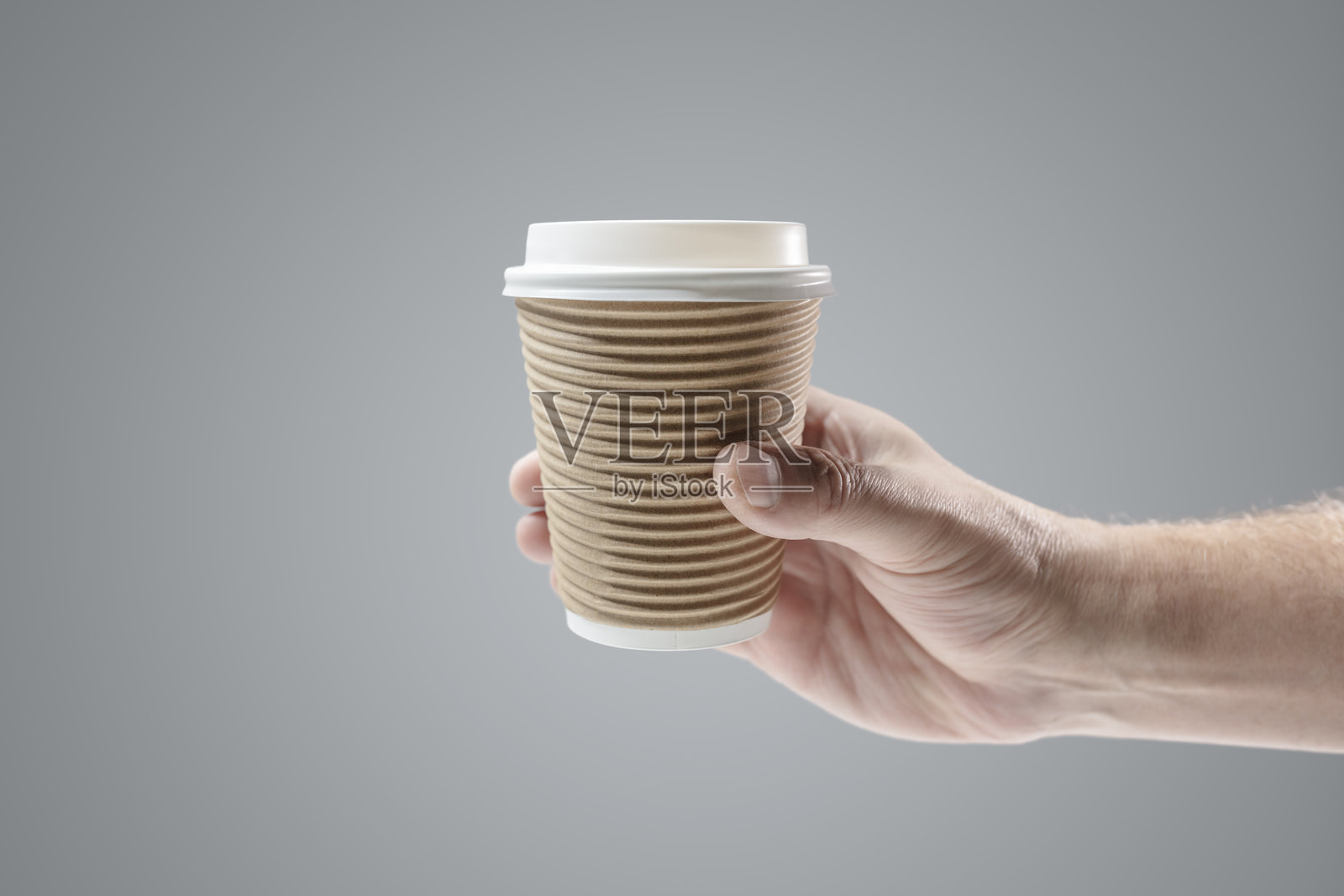 手持外卖纸杯热咖啡,背景为灰色照片摄影图片