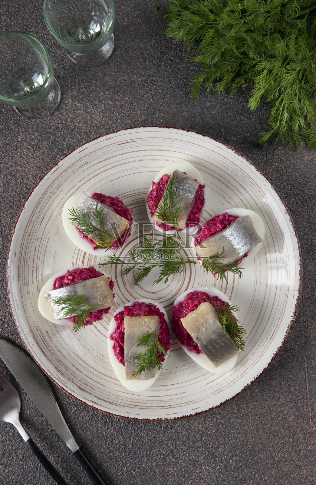 用甜菜和腌鲱鱼填充的鸡蛋,配以莳萝,背景为棕色照片摄影图片