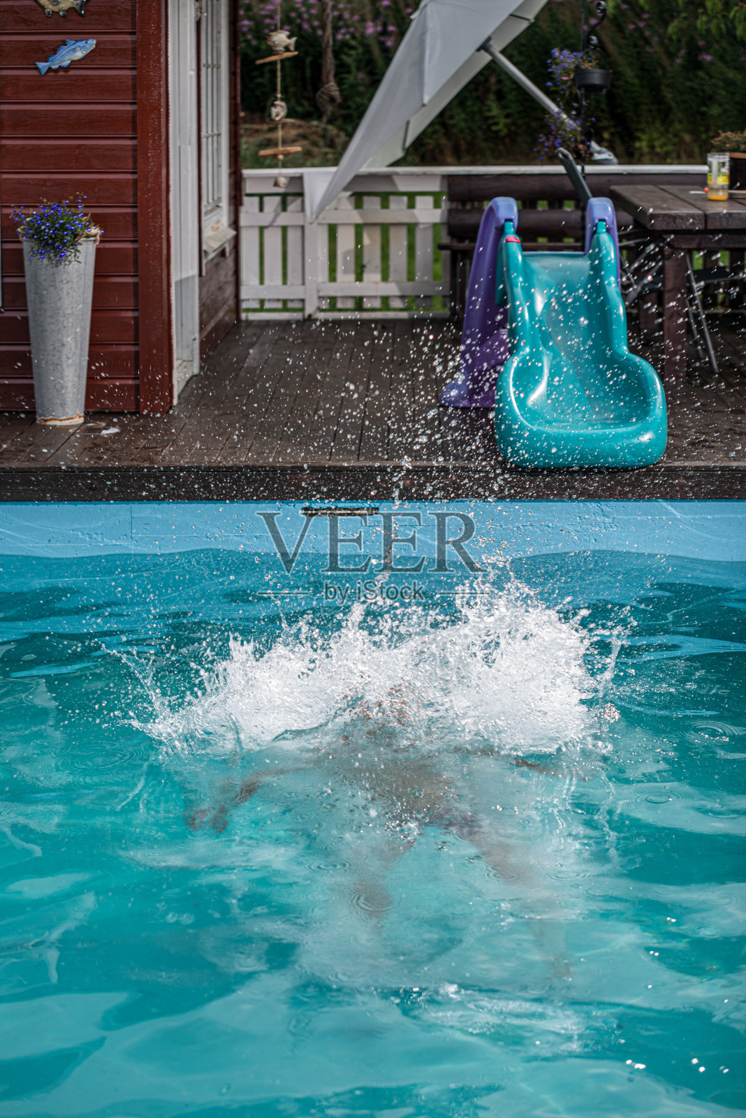 一个人跳入泳池后溅起的水花。照片摄影图片