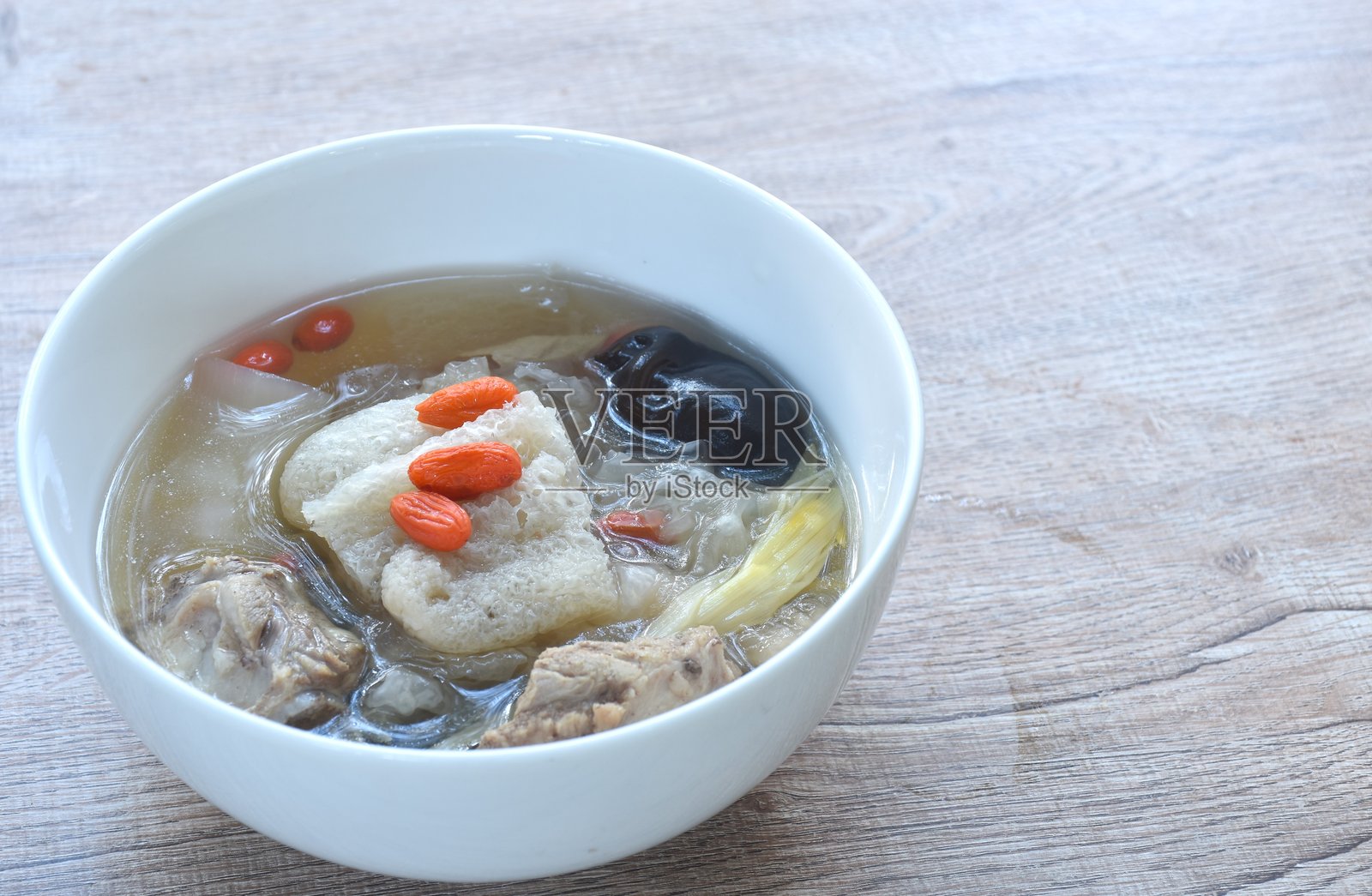 清汤中煮竹荪、猪骨和黑木耳蘑菇照片摄影图片