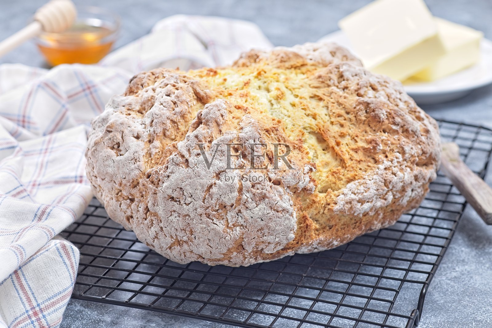 新鲜出炉的苏打面包放在冷却架上,背景有黄油和蜂蜜,横向构图照片摄影图片