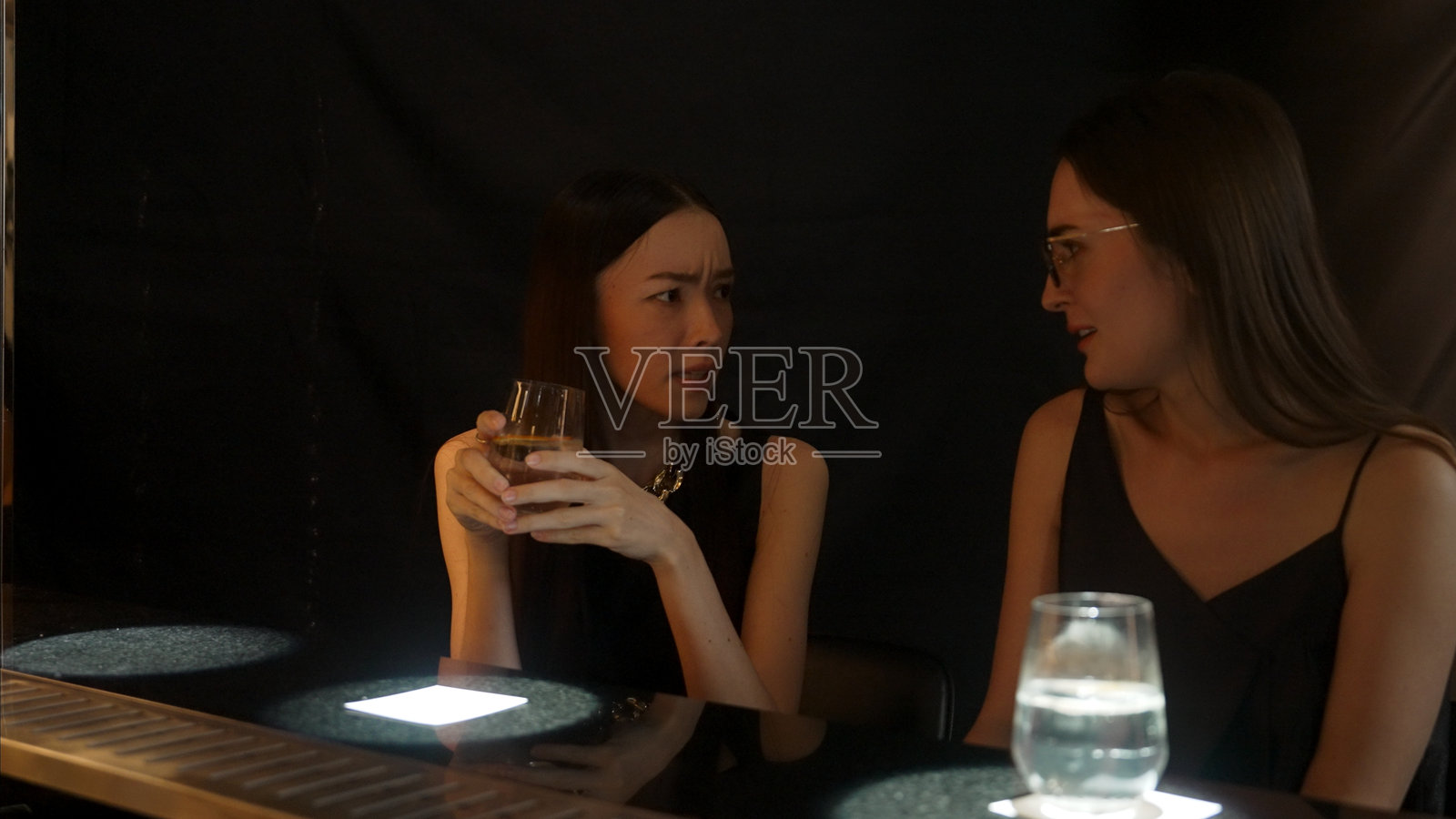 在酒吧与朋友们一起享用饮料的美丽女性。照片摄影图片