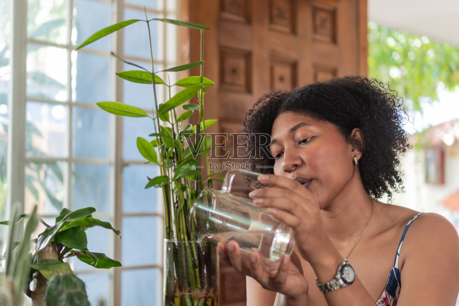 年轻女性在家用玻璃罐浇水植物照片摄影图片