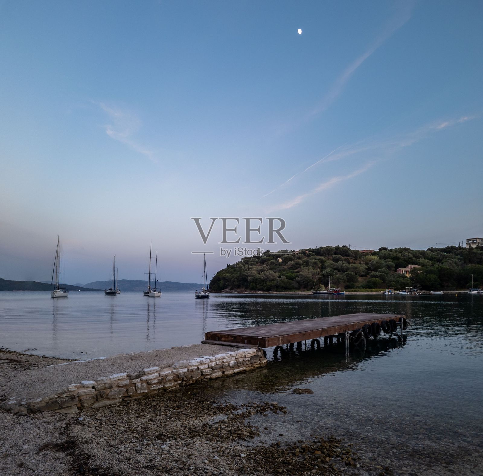 宁静的海边黄昏景色,帆船和码头。照片摄影图片