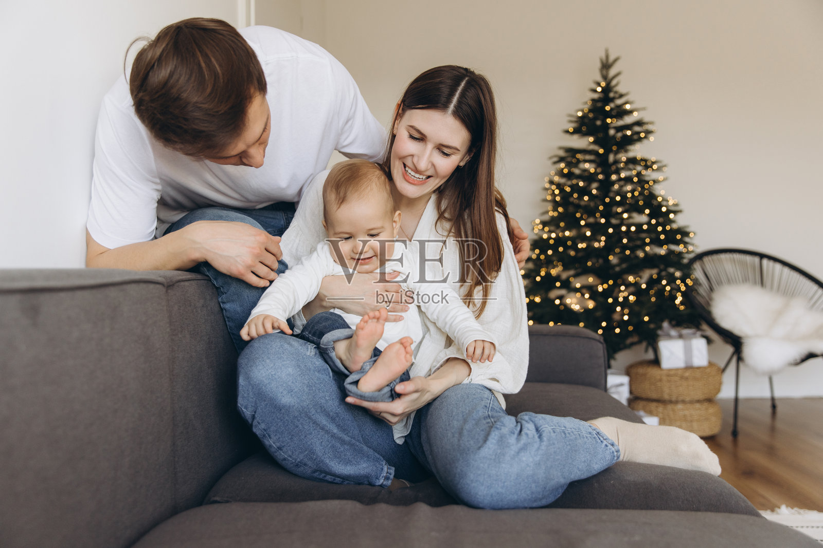 一家人在圣诞树旁的沙发上与宝宝玩耍照片摄影图片