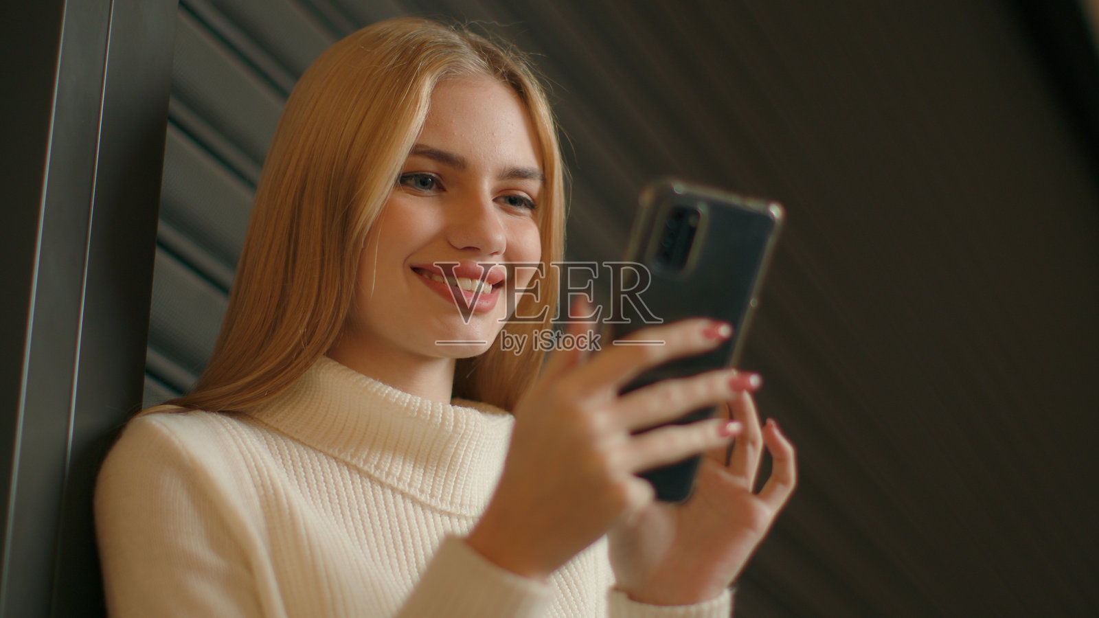 微笑的白人女性学生和女商人正在浏览互联网,通过手机发送信息,快乐的女孩使用智能手机下载视频,冲浪社交网络,年轻的Z世代与现代科技。照片摄影图片