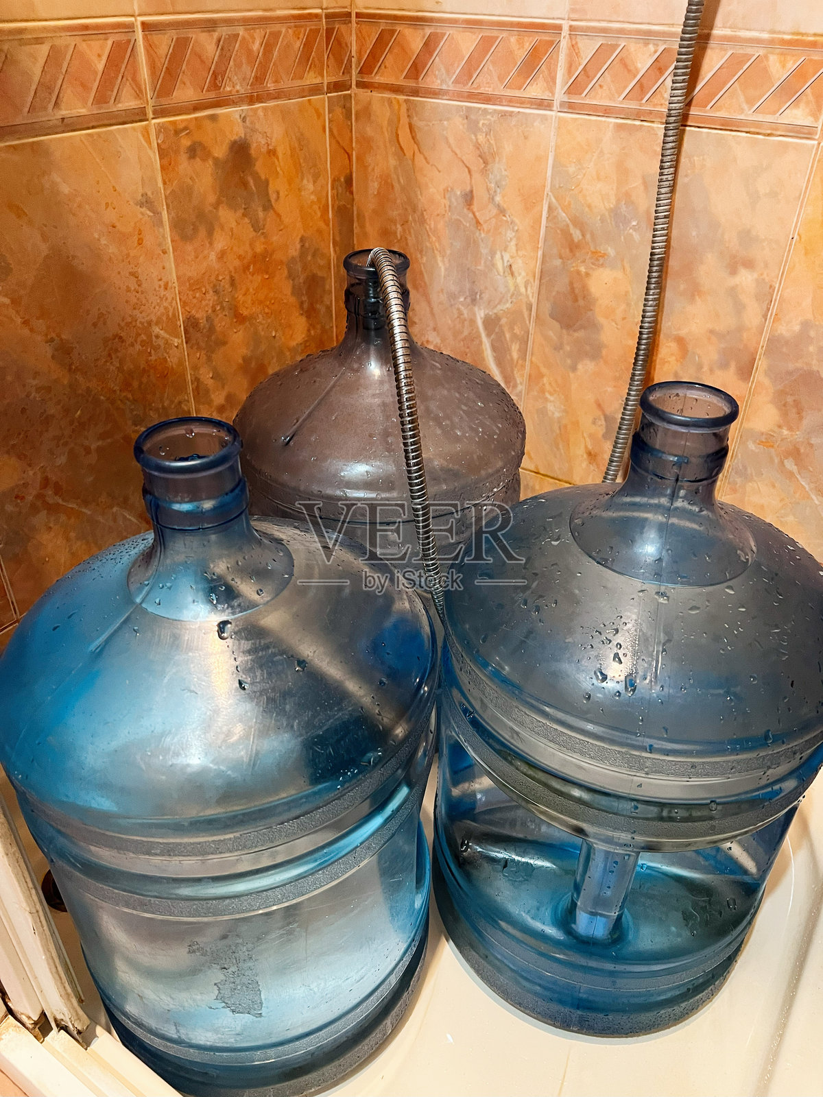 三个大型水壶放在瓷砖浴室的角落里照片摄影图片