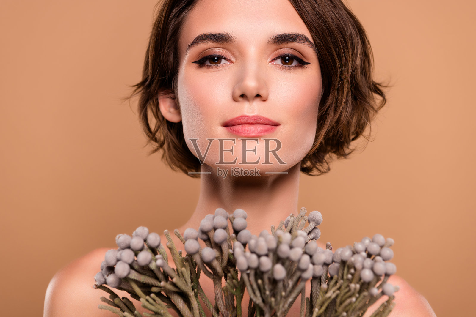 吸引人的女孩手持猫尾草枝,背景为柔和的粉彩色。照片摄影图片