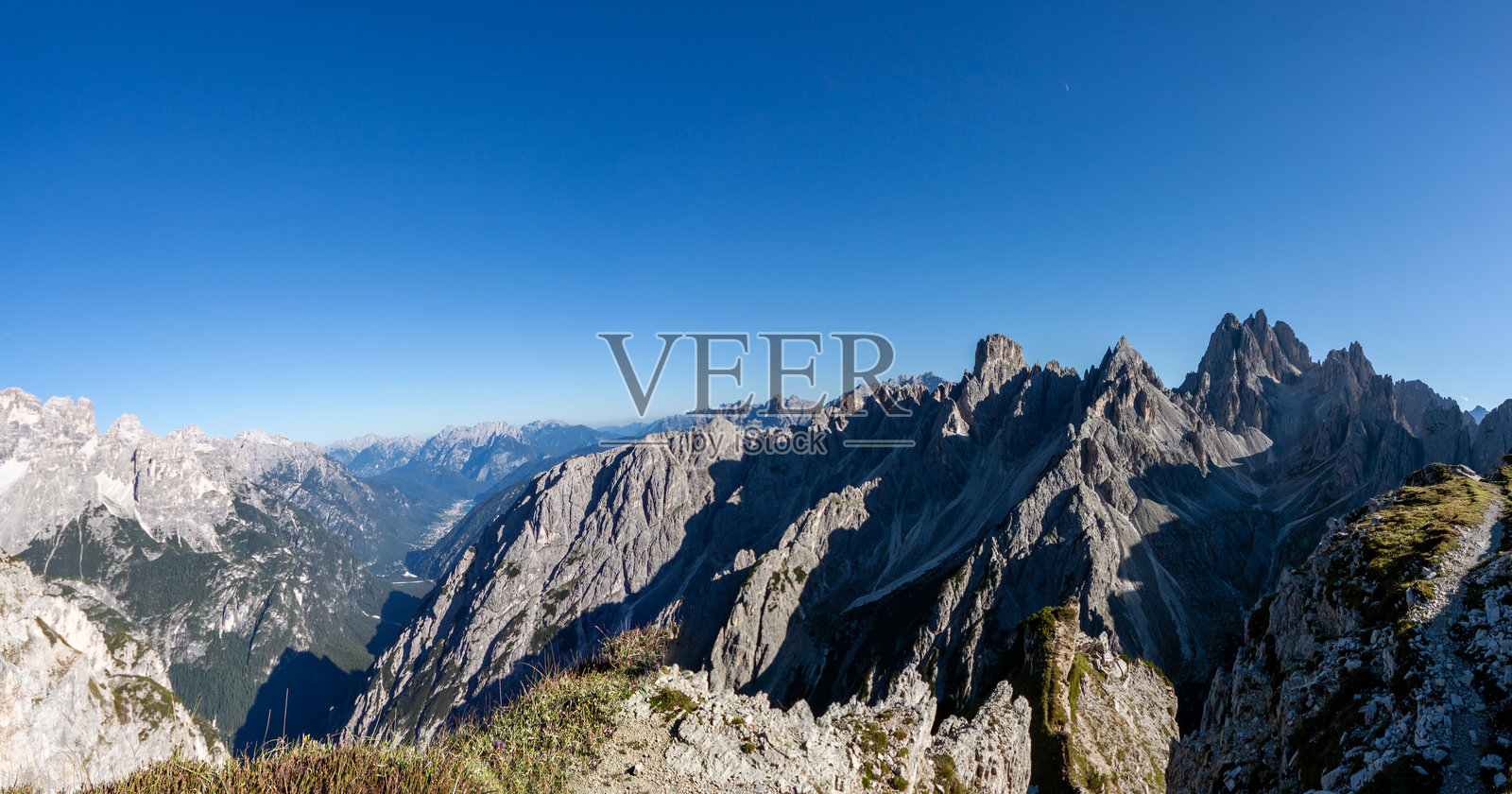 多洛米蒂山脉的 jagged peaks 和深谷,背景是清澈的蓝天。照片摄影图片