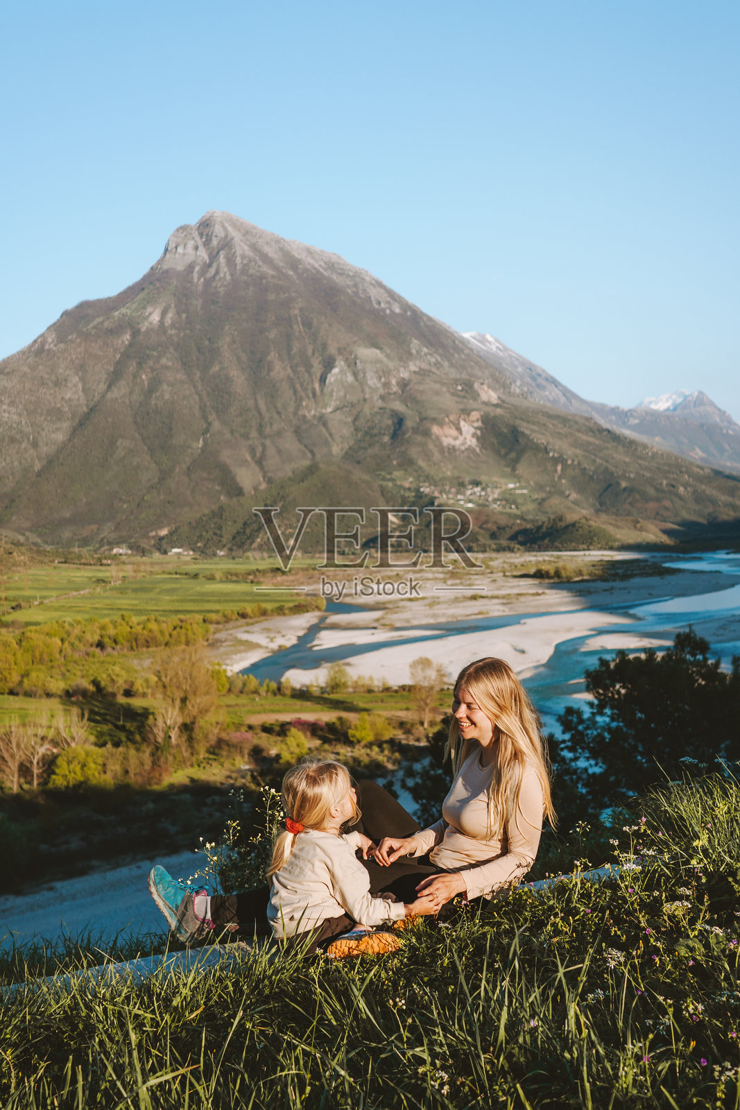 母亲和女儿在阿尔巴尼亚的户外假期中享受乐趣,父母与女儿一起玩耍,欣赏空中山脉和维约萨河的美丽风景。照片摄影图片