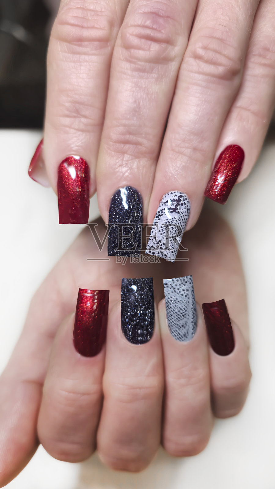 丙烯酸指甲延伸、修甲和前景中的手。蛇皮设计照片摄影图片