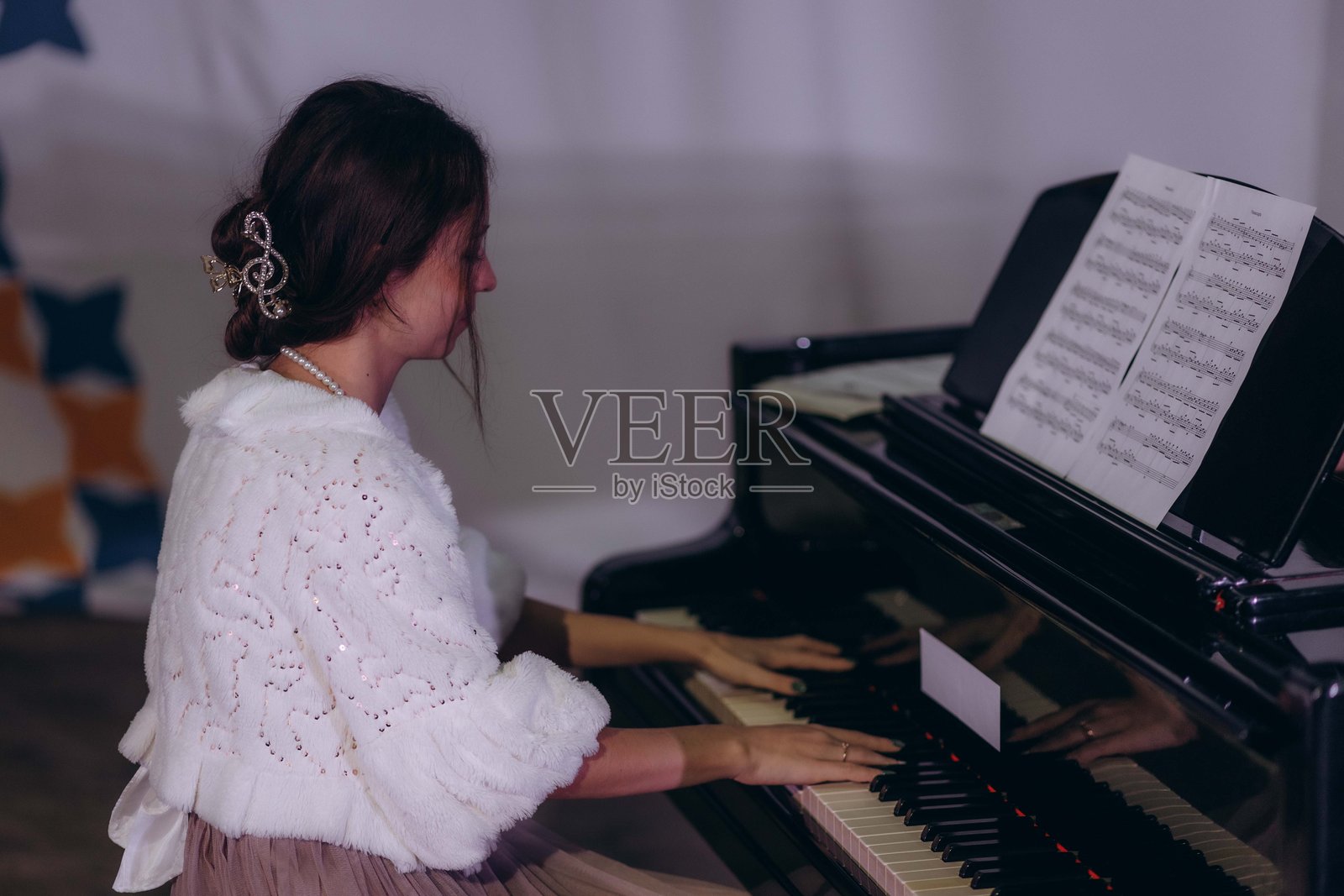 美丽的女人在有白色窗帘的房子里弹钢琴。照片摄影图片
