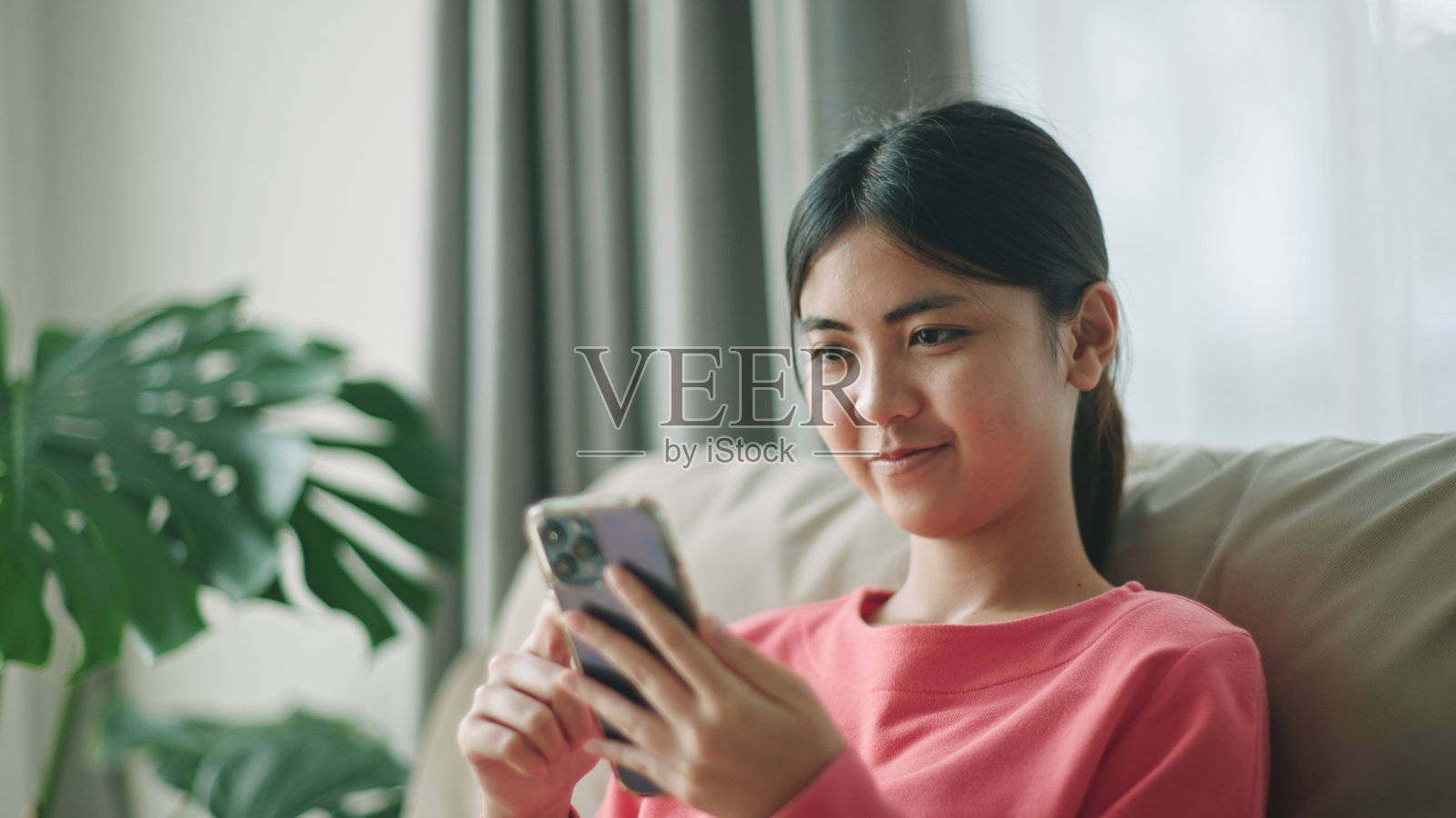 青少年在沙发上使用智能手机。照片摄影图片