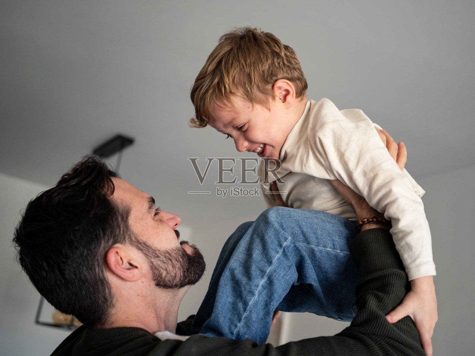 父亲在温馨的客厅里快乐地举起儿子照片摄影图片