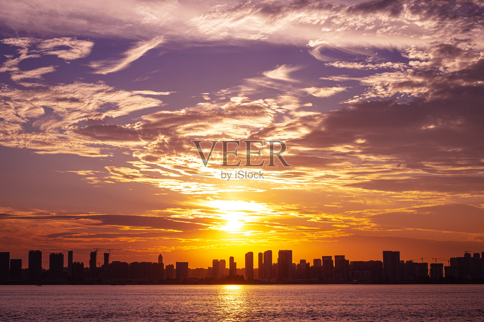 日落时分,现代城市天际线下的戏剧性天空和云彩照片摄影图片