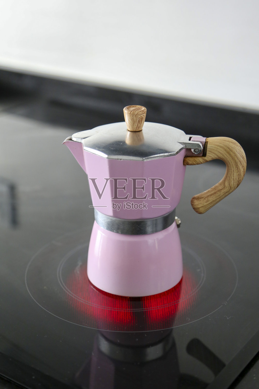 粉色意大利铝制咖啡壶和木柄放置在陶瓷灶台上照片摄影图片