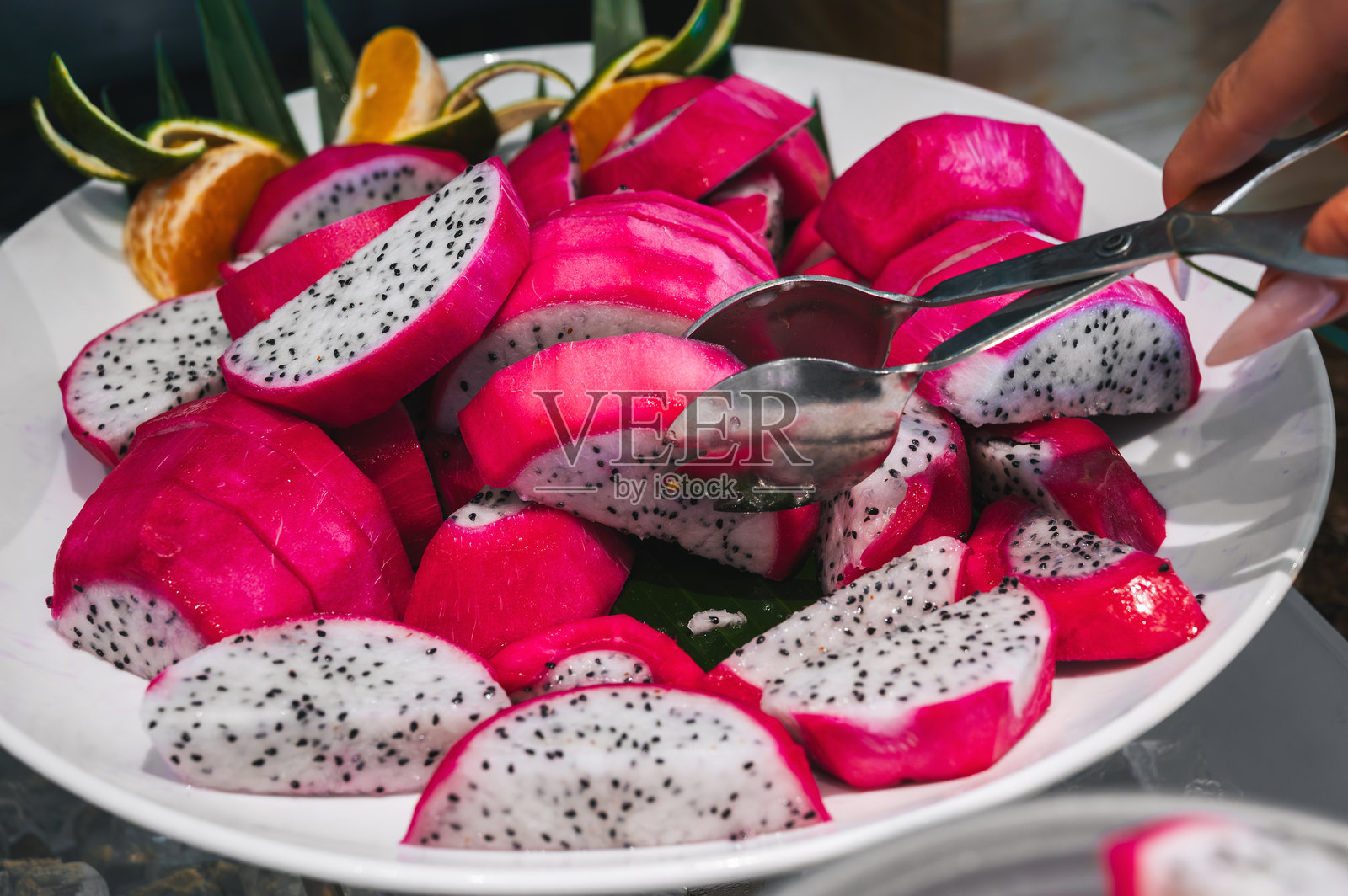 火龙果切片特写,女性手将水果放在盘子上照片摄影图片