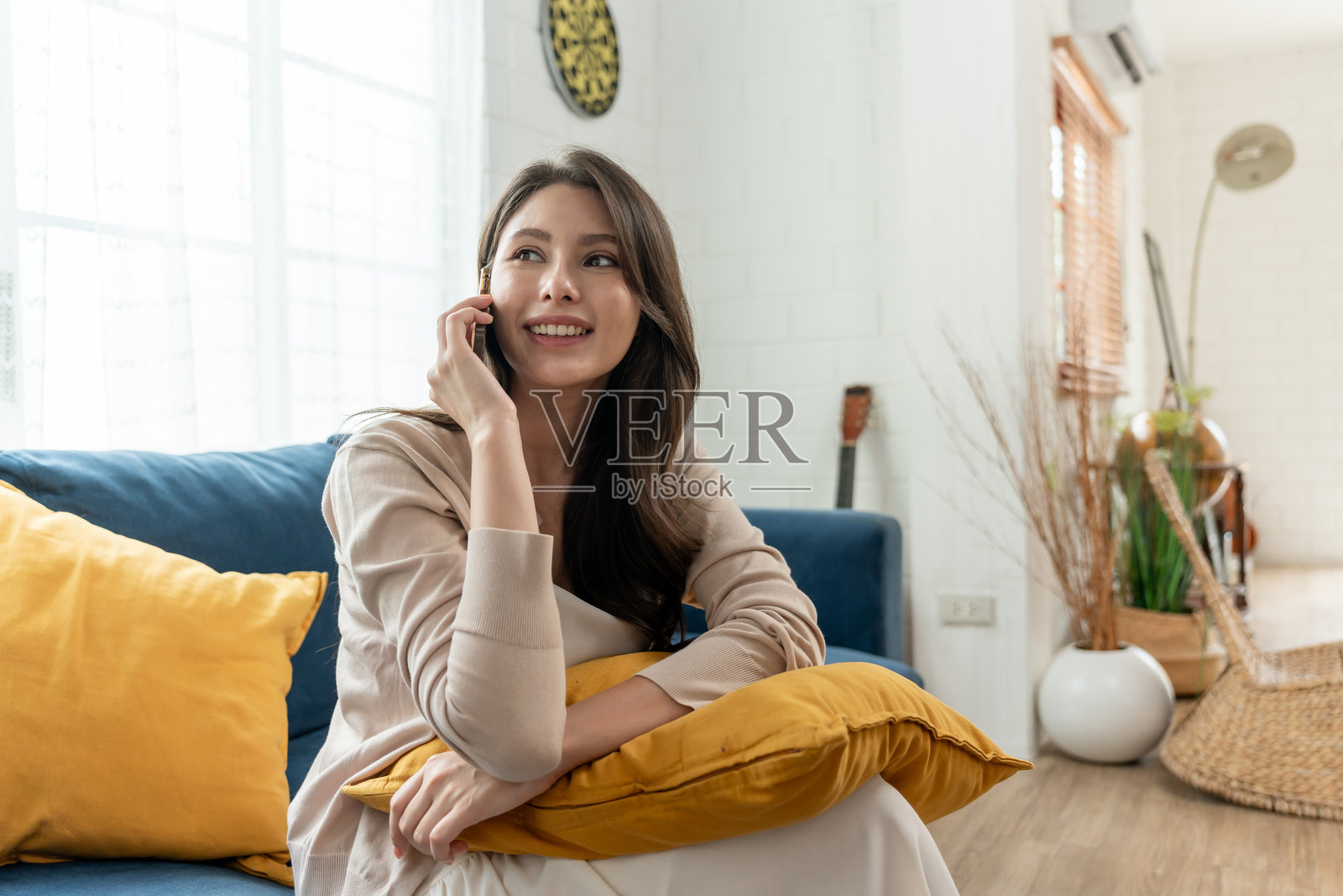 亚洲美丽女孩坐在家中舒适的沙发上。年轻迷人的女人感到快乐和放松,享受假期在家中的闲暇时光。健康与幸福的概念。照片摄影图片