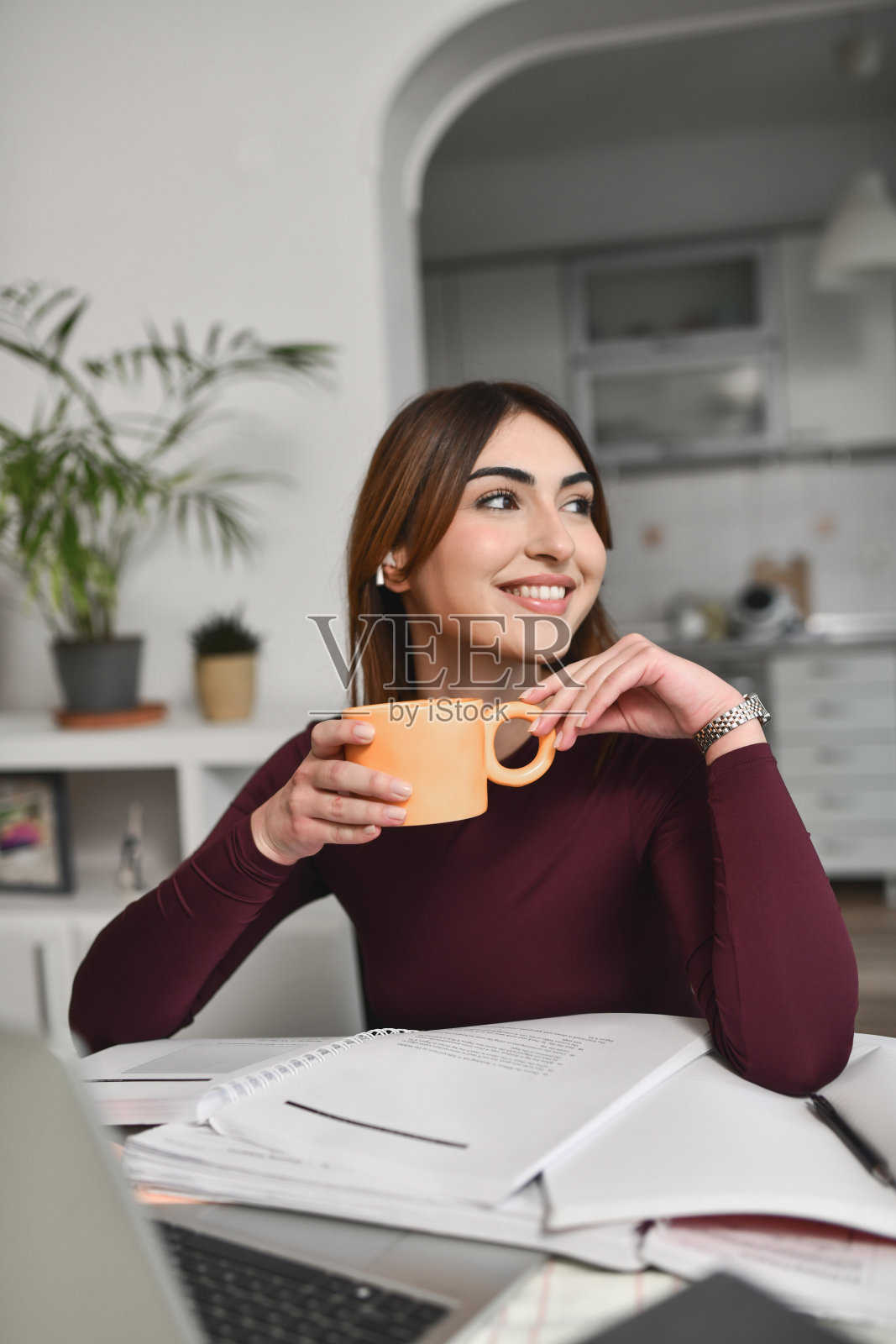 美丽的女人在家工作时,愉快地从窗户观看日落照片摄影图片