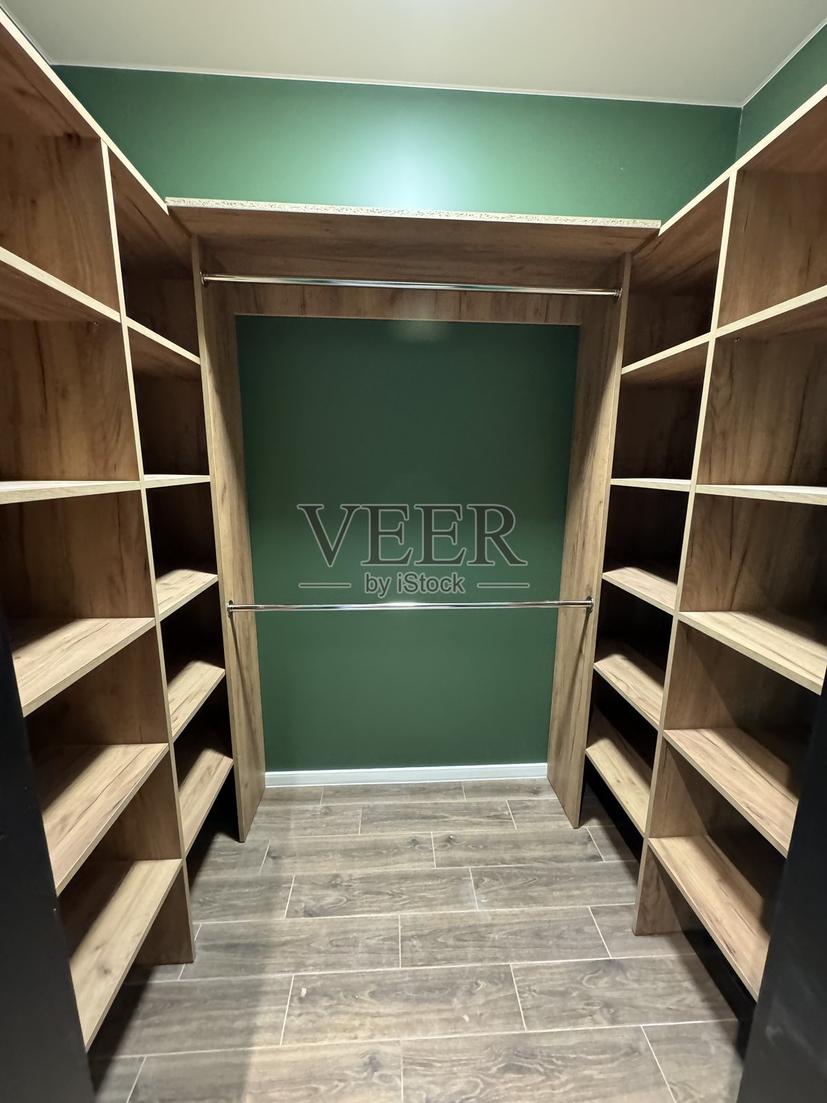 现代步入式衣橱,配有木制架子、绿色墙壁和瓷砖地板照片摄影图片