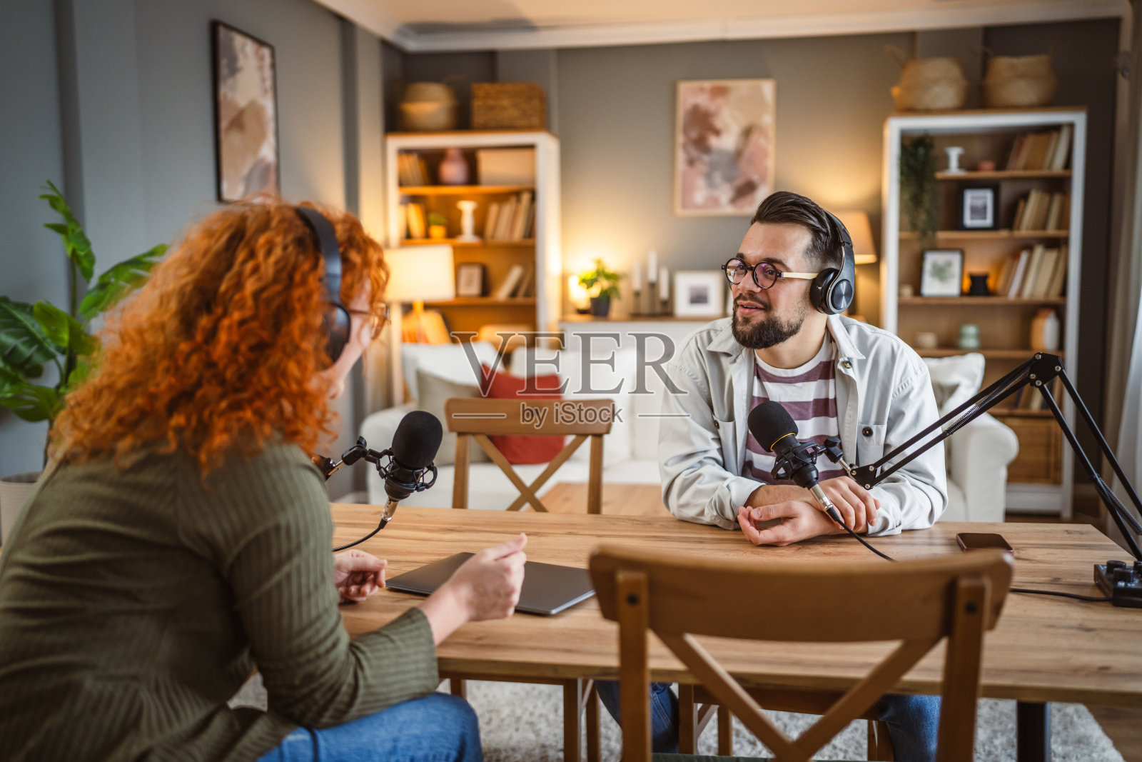成年男性主持人与女性嘉宾在录制播客时提问照片摄影图片